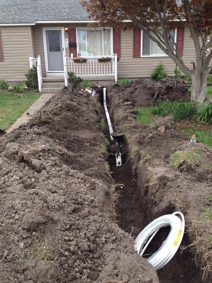 Open trench across a front yard exposing a newly installed sewer line and cleanout riser at a home in Portsmouth VA — Newman's Plumbing Service & Repair